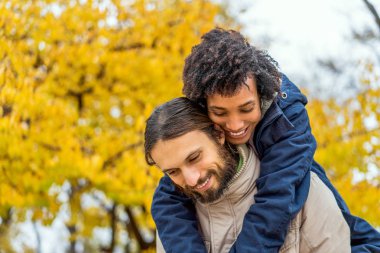 Sonbahar parkında aşık Afrikalı Amerikalı bir kızla gün batımında yürüyüşe çıkan bir adam.