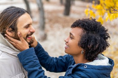 Sonbahar parkında aşık Afrikalı Amerikalı bir kızla gün batımında yürüyüşe çıkan bir adam.
