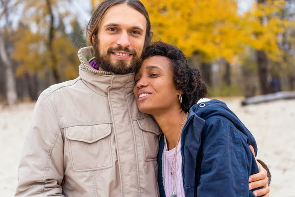 Kerl mit einem verliebten afrikanisch-amerikanischen Mädchen beim herbstlichen Parkspaziergang bei Sonnenuntergang — Stockfoto