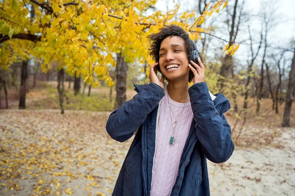 Belle africaine fille dans automne parc écouter de la musique en plein air souriant — Photo