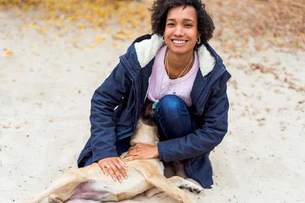 Beautiful african girl in autumn park on nature plays with a dog — Stock Photo, Image