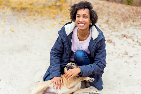 Belle fille africaine dans le parc d'automne sur la nature joue avec un chien — Photo