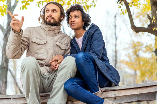 Jongen met een Afrikaans amerikaans meisje in liefde in de herfst park lopen bij zonsondergang — Stockfoto