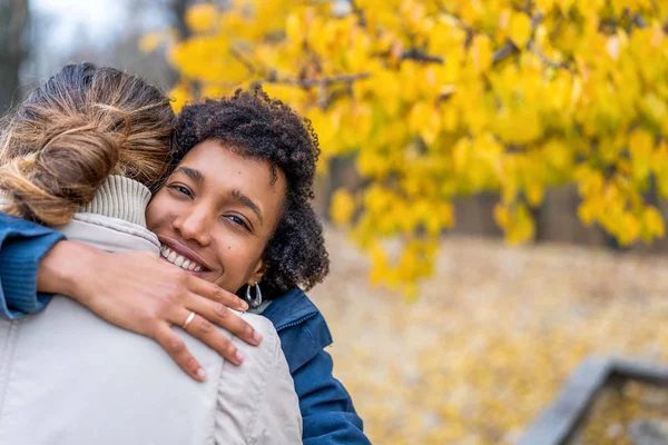 Kille med en afrikansk amerikansk flicka kär i höst park promenad vid solnedgången — Stockfoto