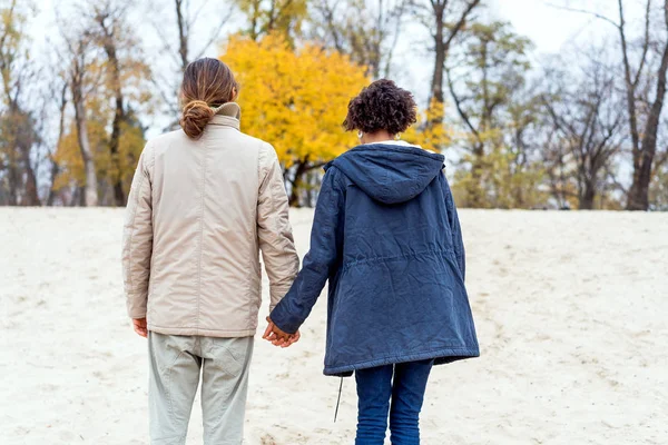 Chico con un afroamericano chica en amor en otoño parque caminar al atardecer — Foto de Stock