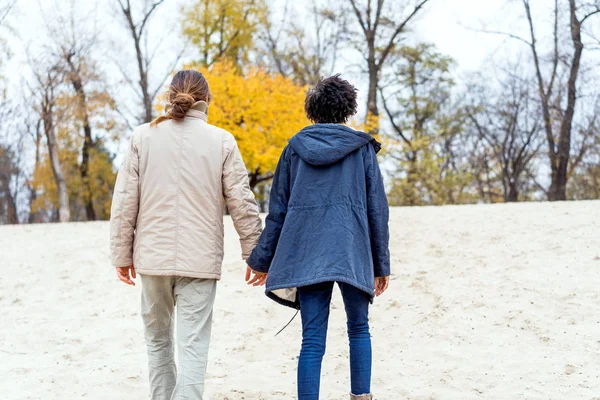 Sonbahar parkında aşık Afrikalı Amerikalı bir kızla gün batımında yürüyüşe çıkan bir adam. — Stok fotoğraf