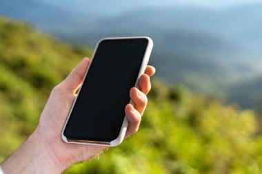 Gün batımında dağda elinde telefon tutan bir adam.