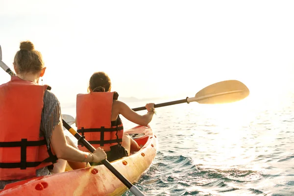 情侣皮划艇在一起。美丽的年轻夫妇一起在湖上划船，日落时面带微笑 — 图库照片