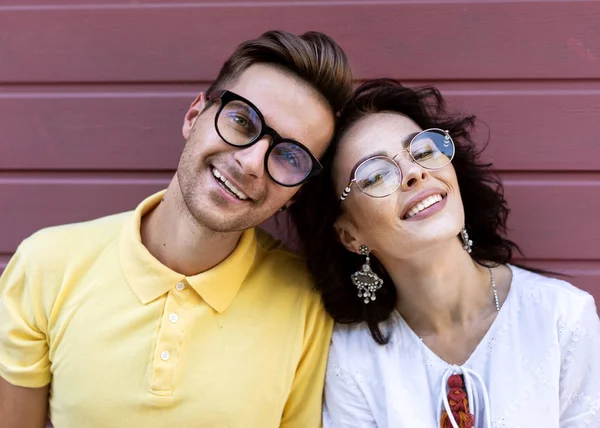 Mladý módní pár na růžovém pozadí — Stock fotografie
