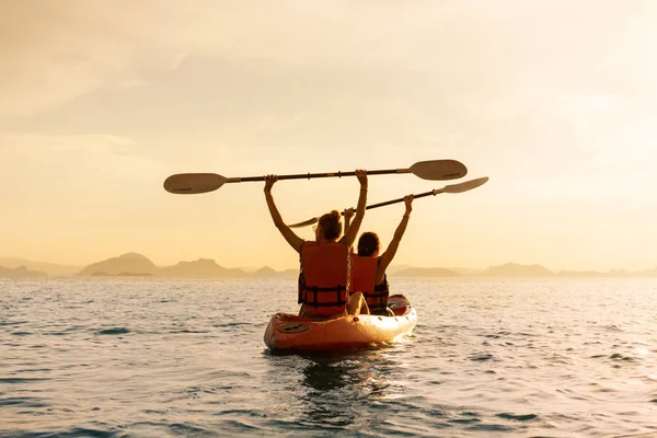 Un paio di kayak insieme. Bella giovane coppia kayak sul lago insieme e sorridente al tramonto — Foto Stock