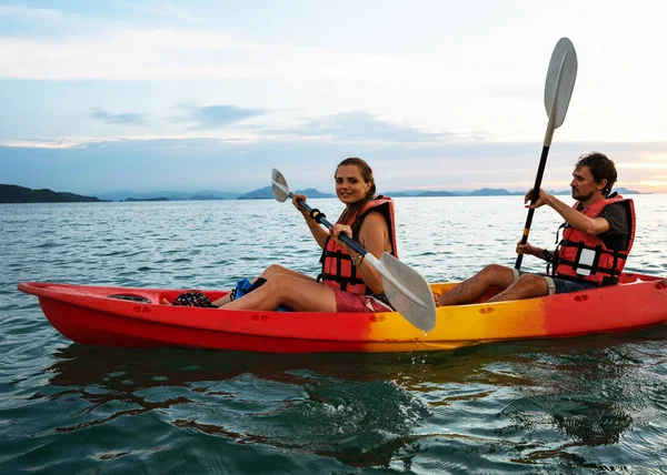 Um par de caiaques juntos. Bela jovem casal de caiaque no lago juntos e sorrindo ao pôr do sol — Fotografia de Stock