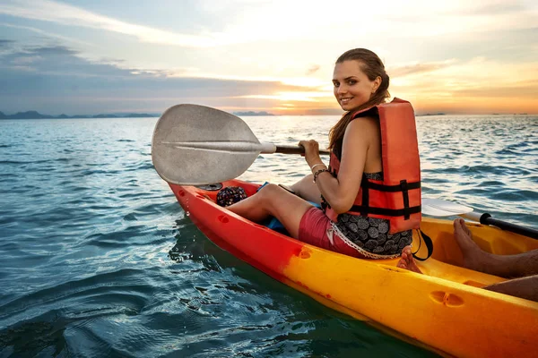 Un par de kayak juntos. Hermosa pareja joven kayak en el lago juntos y sonriendo al atardecer —  Fotos de Stock