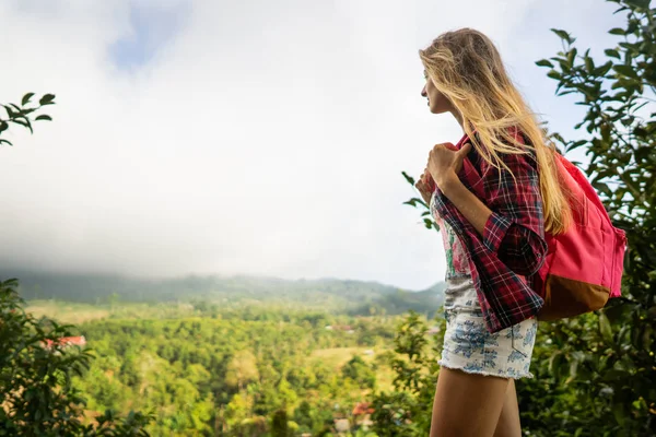 Turista menina com uma mochila nas montanhas fica com as costas — Fotografia de Stock