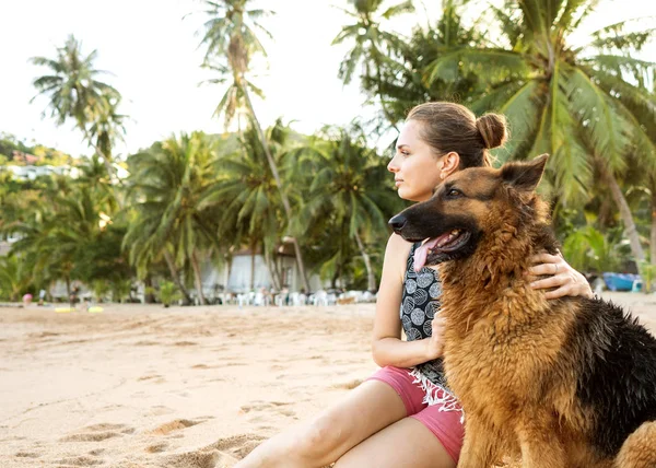 Chica con un perro en una playa tropical entre palmeras y arena en Tailandia —  Fotos de Stock