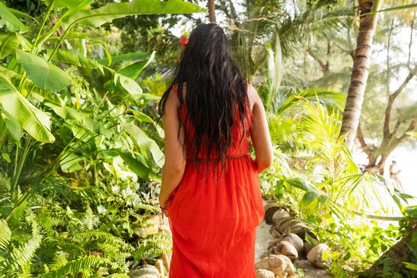 Meisje in een rode jurk tussen tropische palmbomen in Thailand bij zonsondergang — Stockfoto