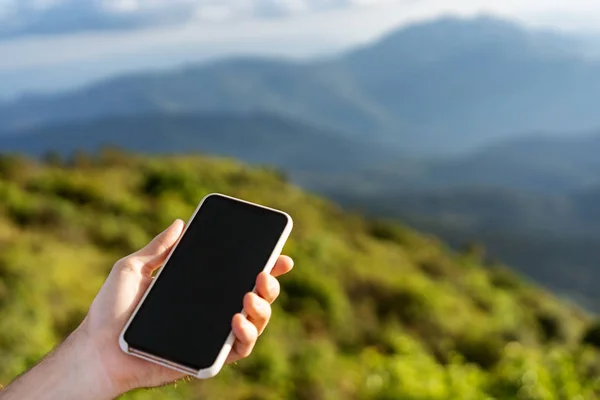 Guy holding a phone in the mountains at sunset — Stock Photo, Image