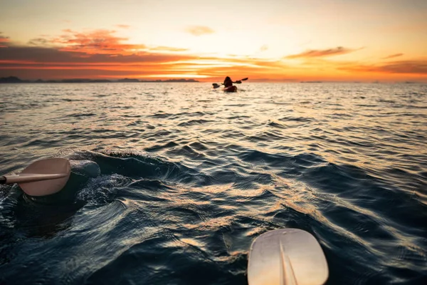 在皮划艇上迎接日落 后视镜 一对年轻夫妇在海上划船 背景是夕阳 — 图库照片