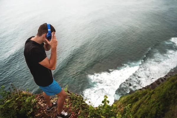 Chlap Sluchátkách Stojí Útesu Oceánu Při Západu Slunce Bali — Stock fotografie