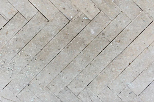 A close-up of an old gray faded parquet covered with dust and dirt. Result of repair. Cleaning and cleaning required