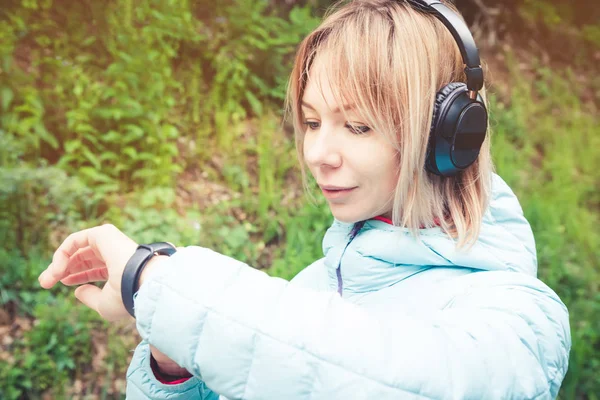 Portret młodego fitness kobieta ogląda jej inteligentny zegarek podczas przerwy szkolenia sportowego. Sportsmenka sprawdzanie impuls fitness inteligentny zegarek urządzenia w lesie. — Zdjęcie stockowe