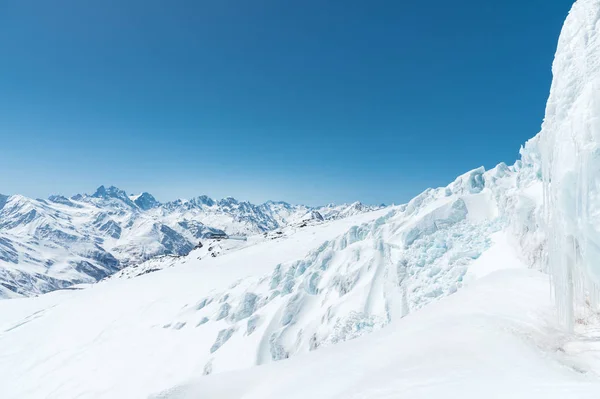 Een grote besneeuwde gletsjer hoog in de bergen tegen de achtergrond van de Kaukasus en de blauwe hemel — Stockfoto