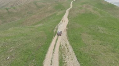 Off-road araç ile akşam Dağları ve yaylaları fon karşı bir dağ yolunda gidiyor. Video wrapabort hava 4 k 100mbps vurulur