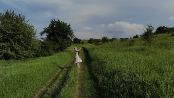 Jovencita alegre caminando descalza en un camino rural. Vista aérea. Tomado en Mavik Air 4k 100kbps — Vídeos de Stock