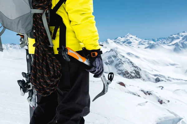 Un alpinista tiene una piccozza alta sulle montagne innevate. Primo piano da dietro. sport all'aperto estremi di arrampicata all'aperto con attrezzature alpinistiche — Foto Stock