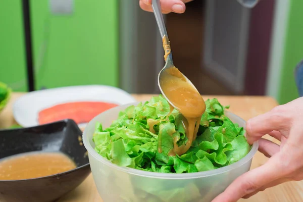 Tangan wanita menambahkan saus selada dari daun selada. Dapur rumah. Tasty sehat dan sehat makanan — Stok Foto