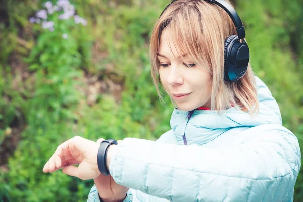 Portret młodego fitness kobieta ogląda jej inteligentny zegarek podczas przerwy szkolenia sportowego. Sportsmenka sprawdzanie impuls fitness inteligentny zegarek urządzenia w lesie. — Zdjęcie stockowe