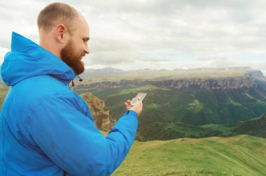 Mavi bir ceket ve Beyaz Peyzaj bir plato ile arka planda arka plan üzerinde bir pusula kullanarak hipster adam