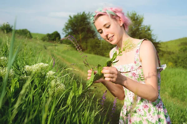 Retrato de uma jovem menina bonita feliz com cabelo multi-colorido recolhe flores ao lado de uma estrada rural ao pôr do sol. O conceito de harmonia humana com a natureza da primavera e da felicidade — Fotografia de Stock