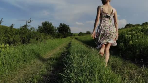 Εύθυμη νεαρή κοπέλα περπάτημα χωρίς παπούτσια σε επαρχιακό δρόμο. Λαμβάνονται στον αέρα Mavik 4k 100kbps — Αρχείο Βίντεο