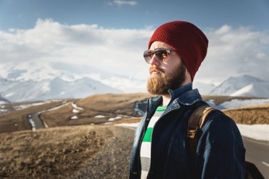 Sakal ve bıyık Dağları arka planı poz güneş gözlüğü takıyor hipster genç adamla