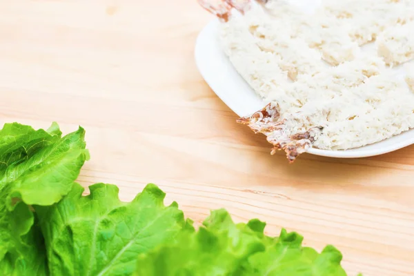 Los langostinos crudos en el pan rallado cerca de la ensalada hortalizas frescas se acercan en el plato a la mesa. Comida casera sabrosa y saludable — Foto de Stock