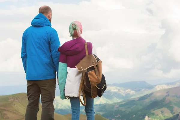 Um par de turistas hipster está de pé ao lado uns dos outros nas montanhas contra o pano de fundo do planalto de vales e céu. Descanse nas montanhas. Viajando em pares — Fotografia de Stock