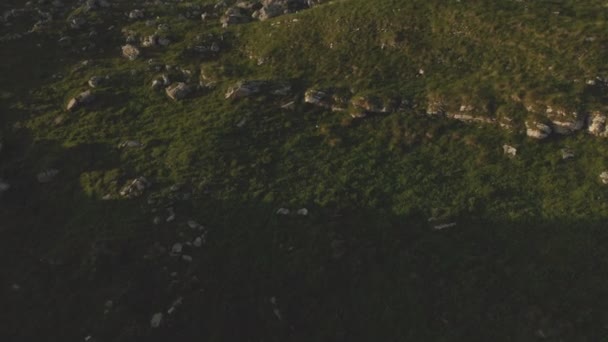 Uma vista de cima em um vale repleto de pedras enormes no sopé de um penhasco alto. Um panorama do pôr-do-sol do Cáucaso com uma volta. Revisão do lugar épico em 4k 100mbps — Vídeo de Stock
