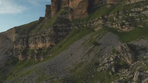 Полет по скалистым скалам у подножия эпических скал плато на Северном Кавказе. Полет над зелеными полями, усыпанными камнями в 4k 100 мб / с — стоковое видео