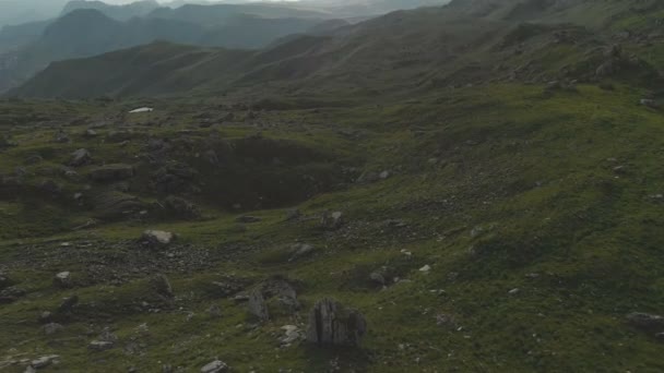 En vy från ovan på en dal beströdd med stora stenar vid foten av en hög klippa. En sunset panorama över Kaukasus med en sväng. Översyn av den episka platsen i 4 k 100 Mbps — Stockvideo