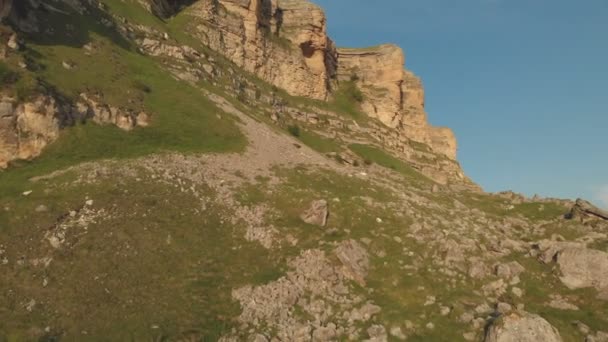 Vol le long des falaises rocheuses au pied des falaises épiques du plateau du Caucase du Nord. Photographie aérienne Vol au-dessus de champs verts parsemés de pierres en 4k 100mbps 