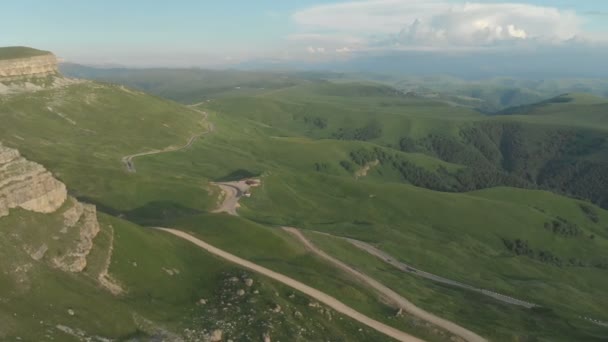 AERIAL: Vuelo sobre un alto acantilado rocoso, revelando una vista del paso en Rusia en el norte del Cáucaso. Fotografía aérea de la carretera al atardecer. Vuelo junto a la roca — Vídeos de Stock