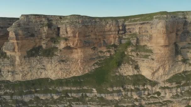 Antenn: Flygning över en hög klippa klippa, avslöjar en syn på passet i Ryssland i norra Kaukasus. Flygfotografering av vägen i den nedgående solen. Flyg bredvid berget — Stockvideo