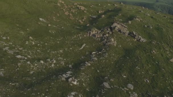 Une vue d'en haut sur une vallée parsemée d'énormes pierres au pied d'une haute falaise. Un panorama coucher de soleil du Caucase avec un virage. Examen de la place épique dans 4k 100mbps — Video