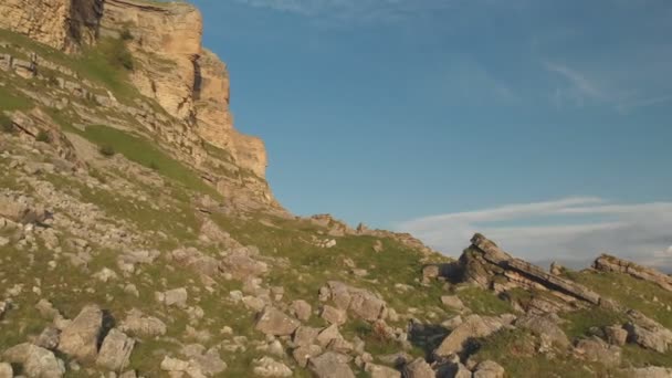 Полет по скалистым скалам у подножия эпических скал плато на Северном Кавказе. Полет над зелеными полями, усыпанными камнями в 4k 100 мб / с — стоковое видео
