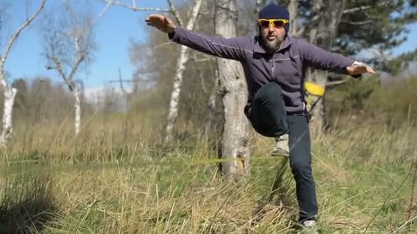 Close-up A man dressed in a hat and beard, stands up to walk in the wind against the background of the Caucasus mountains of the blue sky and clouds — Stock Video