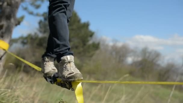 Närbild man går slackline under vinden mot bakgrund av Kaukasus bergen av blå himmel och moln — Stockvideo