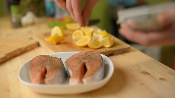 Close-up het meisje besprenkelt een zalm steak aan beide zijden met kruiden voor het frituren — Stockvideo