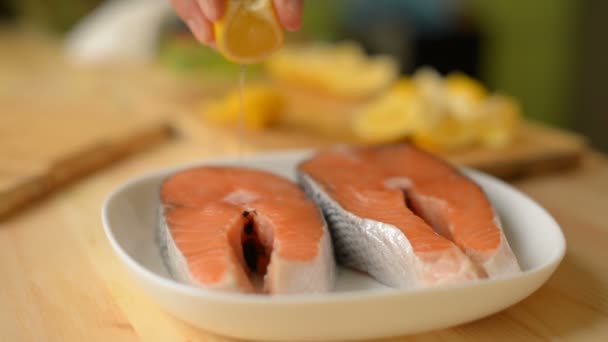 Close-up Una chica exprime un limón rociando un filete de salmón antes de freírlo — Vídeo de stock