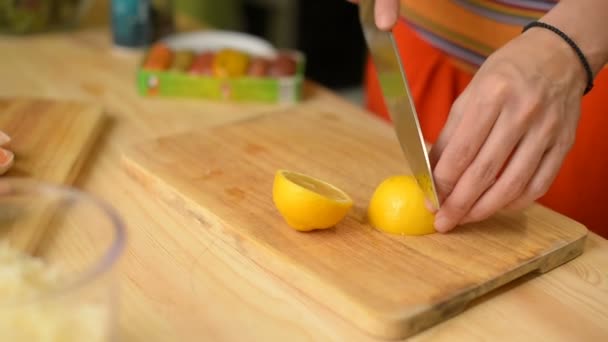 Close-up Girl slices a lemon on a wooden cutting board — Stock Video