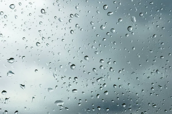 Textured background of window panes with a cloudy background. Natural pattern from a drop of rain on a cloudy background.